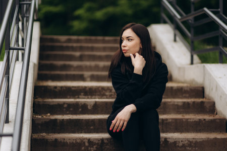 Smiling woman in sportswear sitting on stairs outdoorsの写真素材