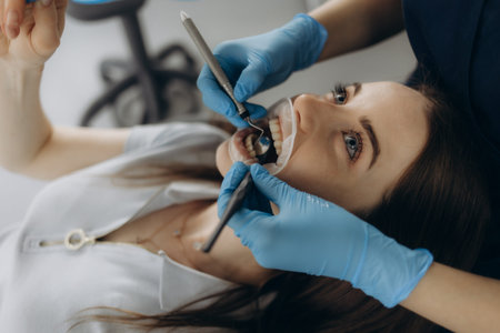 Closeup shot professional dentist with protective surgical mask, doing check up of patient. Dentist...
