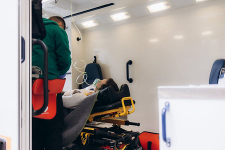 Ambulance interior with male paramedic measuring pulse on senior woman