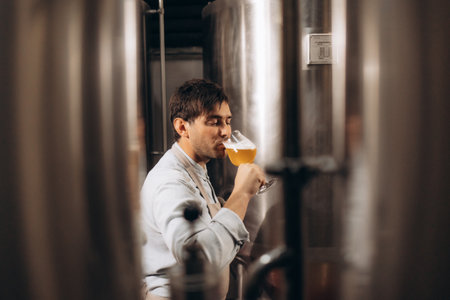 brewer checking beer for qaulity at brewery while holding clipboardの写真素材