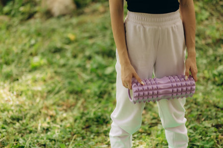 woman holds yoga foam grid roller outdoorsの写真素材