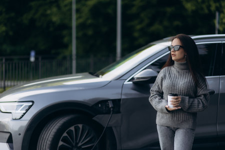 Woman charging electro car at the electric gas stationの写真素材