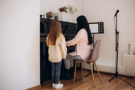 Music teacher shows how to play the piano. Girl learning play piano with teacherの写真素材