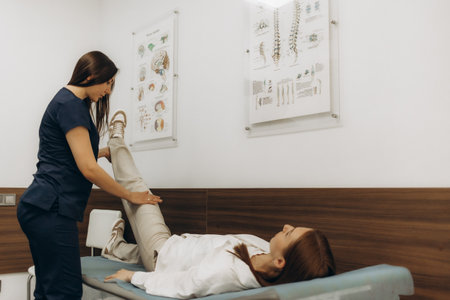 A traumatologist examining a patient's leg on a table during a clinical consultationの写真素材