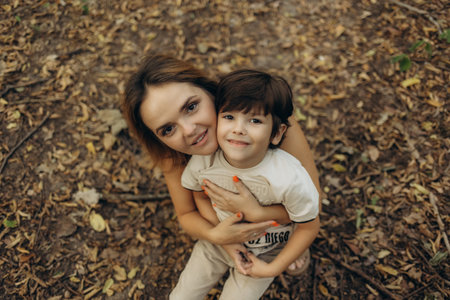 A mother hugs her son while walking in the forestの写真素材
