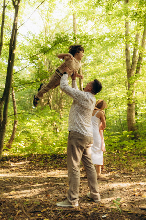 A young family walks in the autumn forest. Happy mum, dad, son and daughterの写真素材