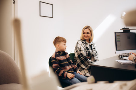 Happy young male doctor give high five to cute small 7s boy patient at consultation with mom in hospital. Smiling pediatrician make deal cheer little kid child in clinicの写真素材