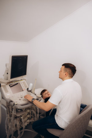 Doctor conducting ultrasound examination of kidneys to child in clinic. Diagnosis of pyelonephritis in children conceptの写真素材