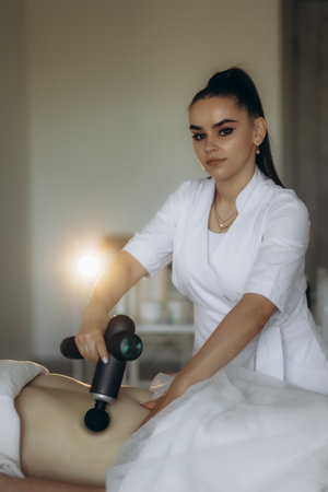 Slim young woman receiving stomach massage in spa salonの写真素材