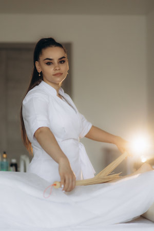 Massage of human foot in spa salon with bamboo sticks. Closeup of legsの写真素材