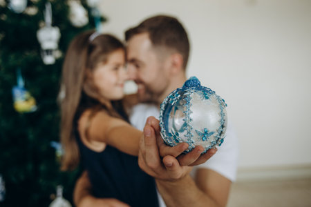 Father giving a present to his happy daughter near Christmas tree at homeの写真素材