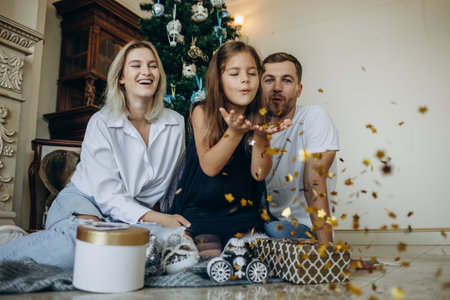 family of four parents pregnant mom and dad and two siblings little boy and girl in stylish clothes in chalet are ready to welcome Christmas and New Year near Christmas tree with gift box presentsの写真素材