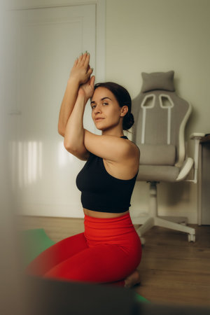 Online yoga meditation home. Attractive young girl sitting in lotus pose near laptop at home. Fit...
