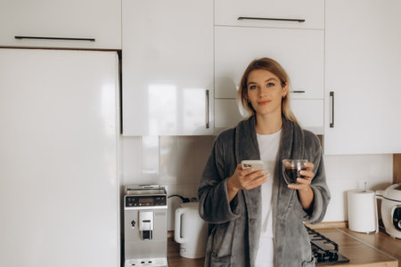 Young woman enjoying fresh aromatic coffee near modern machine in kitchenの写真素材