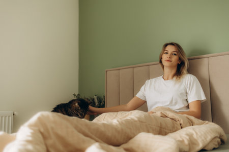 Young woman with cute cat sleeping in bedの写真素材