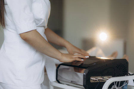 A female massage therapist opens a bag with a device for massageの写真素材