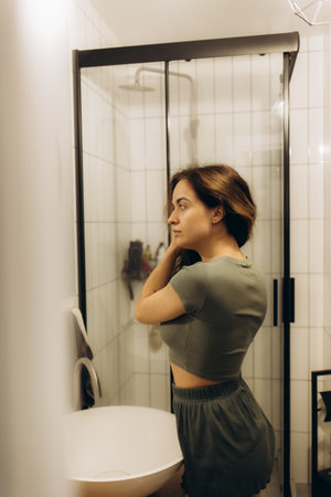 Beautiful young woman near mirror in bathroomの写真素材