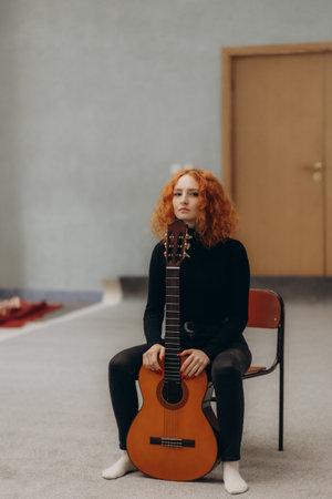 Beautiful young redhead woman plays guitarの写真素材