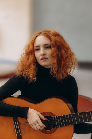 Woman with hat and red hair leaning on a Spanish guitar during her music classes in Arenales del Sol, Spainの写真素材