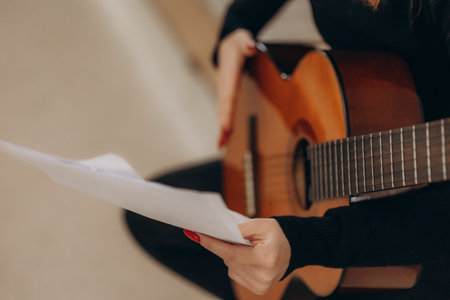 A redheaded woman holds music and plays the guitarの写真素材