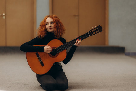 Full body photo of young girl sit floor play guitar wear striped clothes enjoy modern cozy interior flat indoorsの写真素材