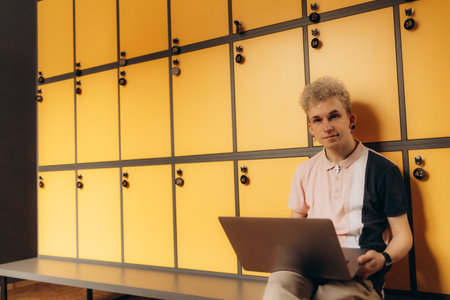 Student using laptop in locker room at collegeの写真素材