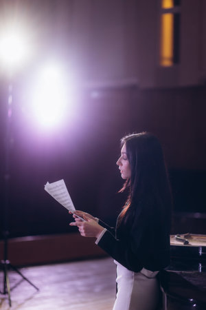Portrait of a female musician with sheet music on the stage, light from spotlights