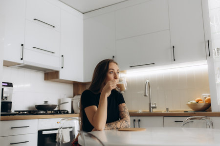 Thinking, drinking coffee and happy woman in home kitchen for relax, peace or calm in morning. Smile, tea cup and person dream of planning future, idea and decision with latte beverage in apartmentの写真素材