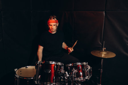 Stylish drummer playing music during rock band indoor club performanceの写真素材