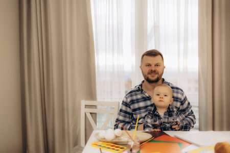 Loving young father lying on floor at home having fun painting with his little son together. Happy playful dad drawing in album with excited small boy child on weekend at home. Hobby concept.の写真素材
