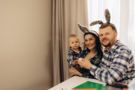 Joyful father, mother and son engaged in Easter egg decorating, sharing smiles and laughterの写真素材