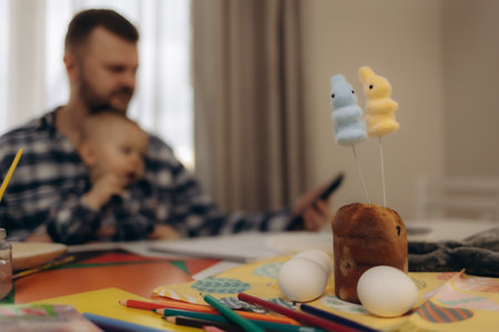 The kid holds the brush with concentration, and his father helps him create the first Easter eggs in his life with a smileの写真素材