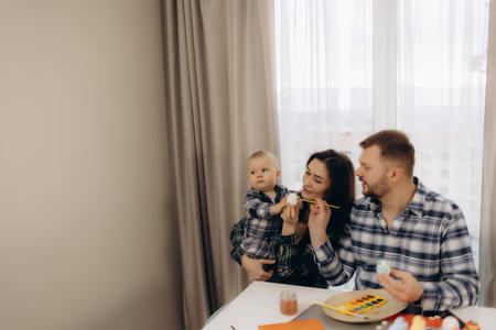 The family prepares for the holiday in a cosy atmosphere, filling each egg with love, warmth and colours of springの写真素材