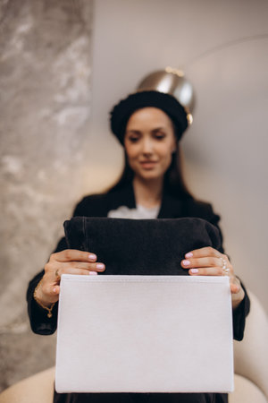 Young woman folding clothes in box on sofa at homeの写真素材