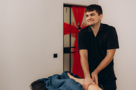 Physiotherapist giving leg massage to a woman in clinicの写真素材