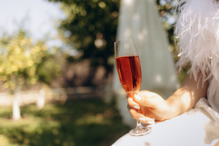 The bride holds a glass of champagne against the backdrop of treesの写真素材