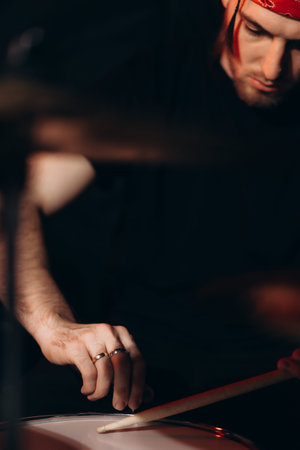A close-up of a musician performing on drums, emitting passion and focus in a creative atmosphere.