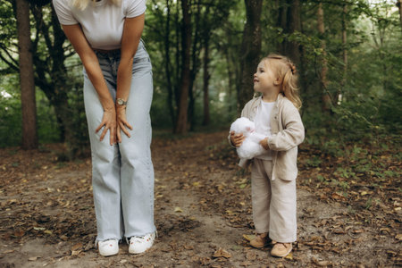Mother and young daughter spend quality time outdoors in a serene woodland, fostering connection and...