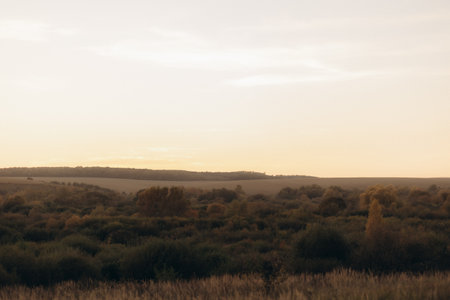 Peaceful scenery featuring a sunset over undulating hills with lush greenery, evoking calmness.の写真素材