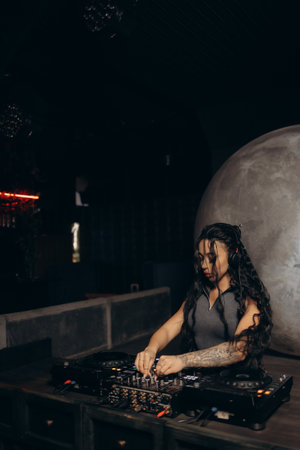 A female DJ mixes music at a nightclub, showcasing skill and passion. The setting features professional audio equipment and a vibrant atmosphere, emphasizing the energy and excitement of nighttime entertainment.の写真素材