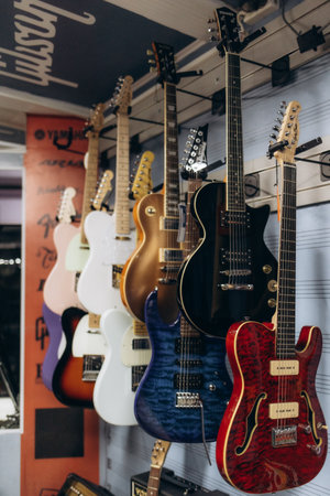 Multiple electric guitars with vibrant designs and various models are showcased in a music shop aisle.の写真素材