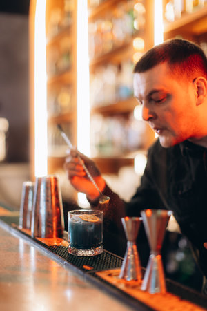 A skilled bartender crafting a distinctive cocktail using unique materials and techniques in a vibrant bar environment.の写真素材