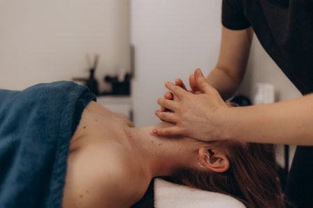 A therapist administers a soothing neck massage to a serene patient in a tranquil spa environment, promoting relaxation and wellness.の写真素材