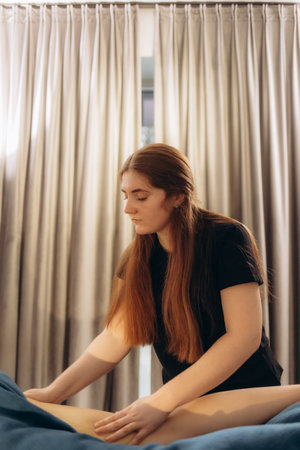 A masseuse performing a therapeutic massage in a serene room, fostering relaxation and wellness. Suitable for depictions of spa treatments, health care practices, and self-care activities.の写真素材
