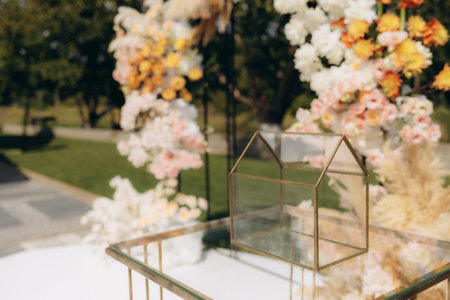 Outdoor wedding scene showcasing a delicate glass house centerpiece, surrounded by colorful floral decorations, adding an elegant and romantic touch to the celebration.の写真素材