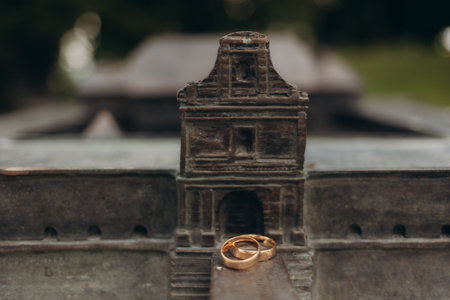 Two golden wedding rings rest on a miniature model of a historical monument, symbolizing love and heritage.の写真素材