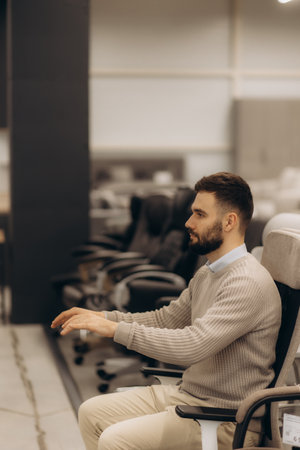 Man in modern office chair display area trying out ergonomic chair models for purchase decision.の写真素材