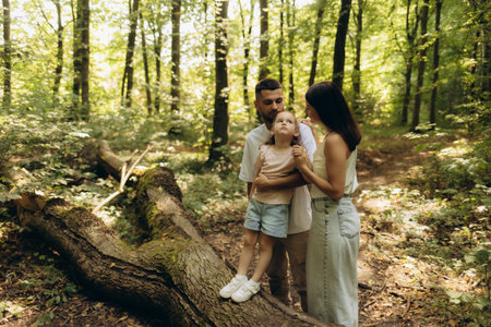 A loving family enjoys a quiet stroll together in a sunlit forest, creating lasting memories amidst nature's tranquility. The moment captures joy, connection, and the beauty of the outdoors.の写真素材