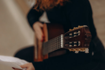 A detailed close-up of a guitar player holding and tuning an acoustic instrument, highlighting the headstock and fretboard, evoking a sense of music practice or performance.の写真素材