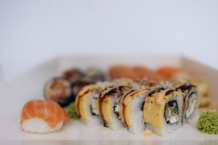A selection of sushi rolls and salmon nigiri arranged beautifully, accompanied by wasabi, with a soft white background highlighting the colors and textures. Perfect for food concepts and culinary photography.の写真素材